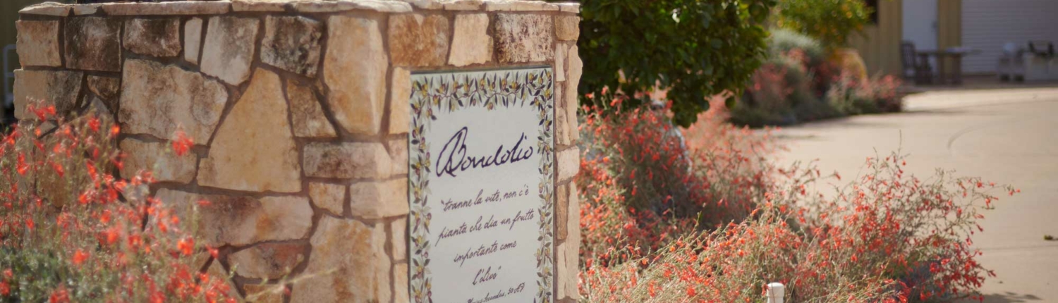 Entrance to Bondolio Olive Grove in Winters, California with stone and plaque and flowers